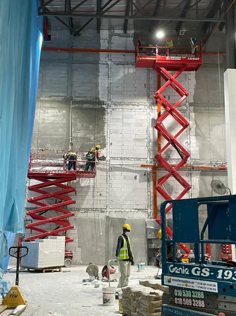 Fire-rated wall works on scissor lifts inside a plant